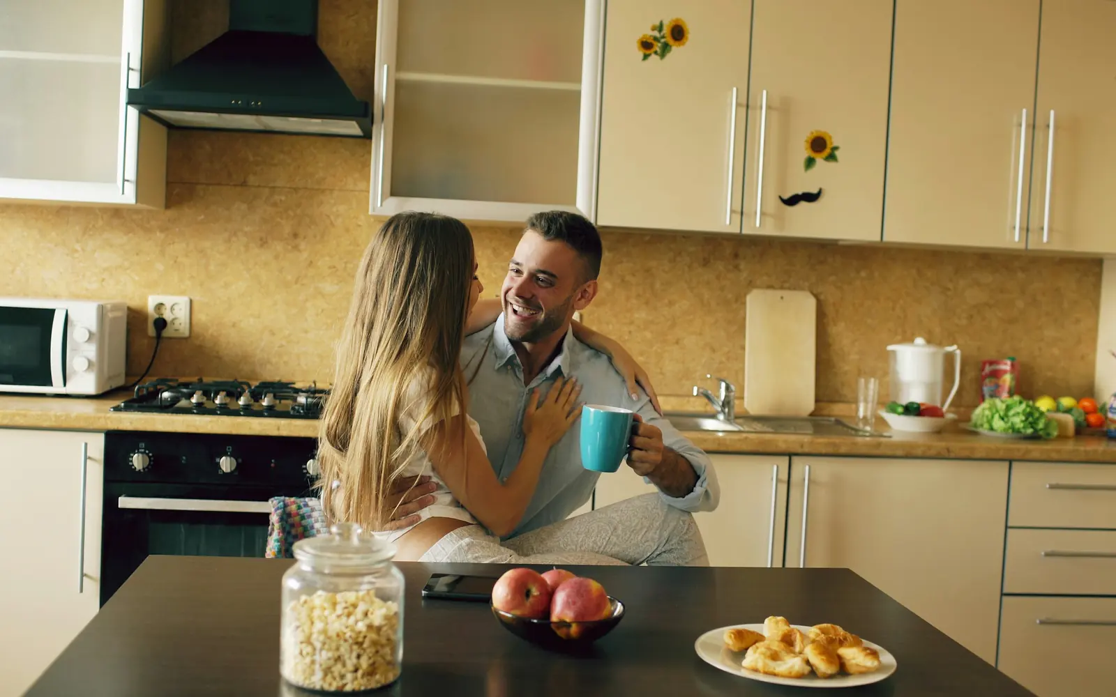 A couple laughing over coffee in a bright kitchen